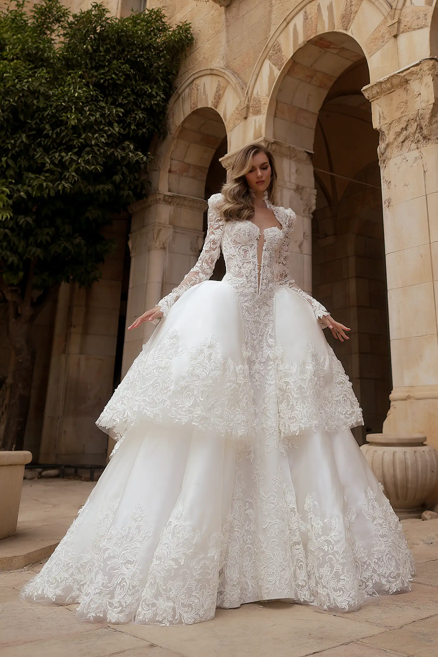 Beaded, dimensional flower embroidered boroque lace and silk organza ballgown, with tiered cutout skirt, high collar, and long puff sleeves. Shown with cathedral-length mantilla veil with beaded dimensional floral appliqué. 