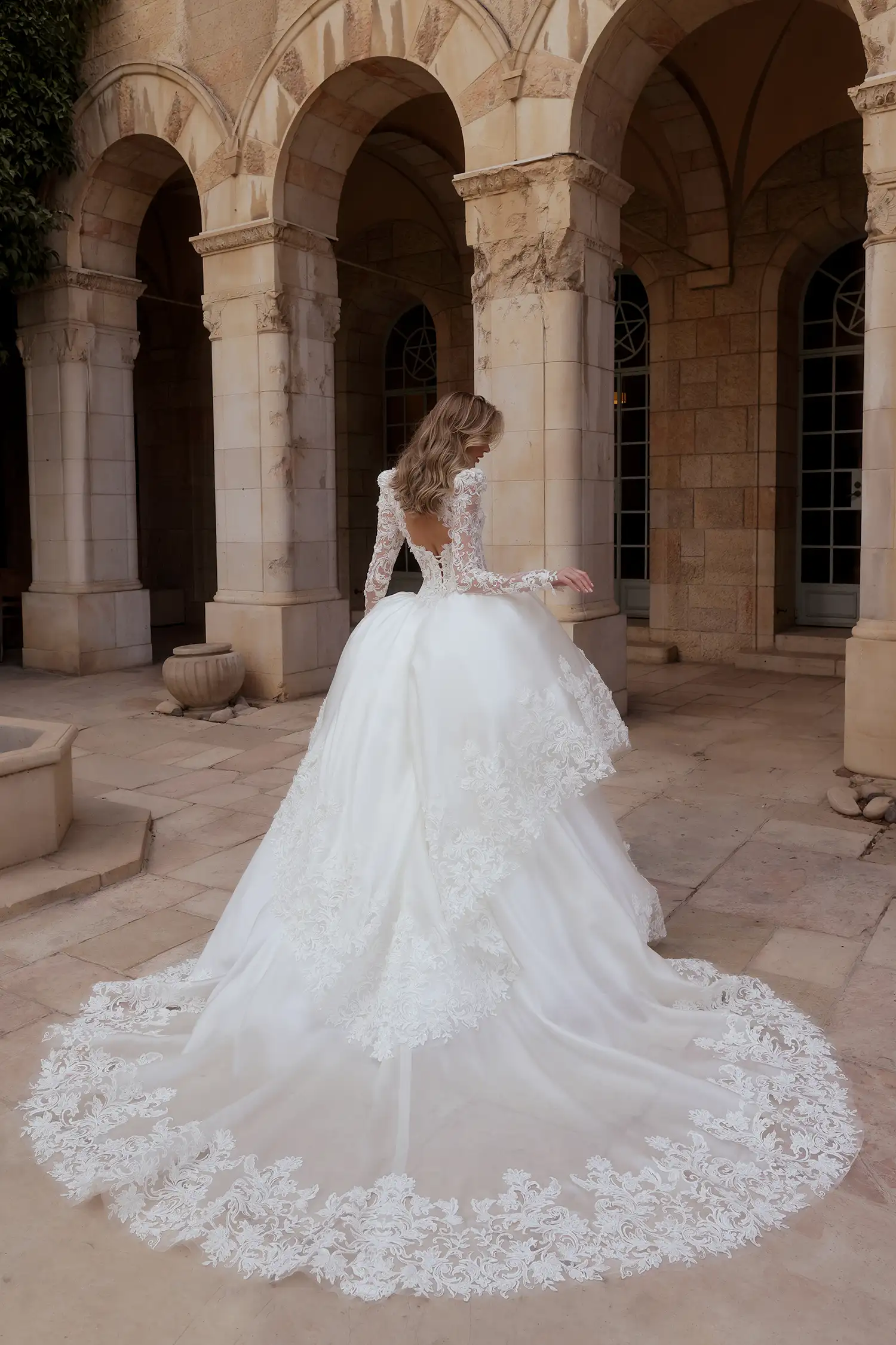 Beaded, dimensional flower embroidered boroque lace and silk organza ballgown, with tiered cutout skirt, high collar, and long puff sleeves. Shown with cathedral-length mantilla veil with beaded dimensional floral appliqué. 