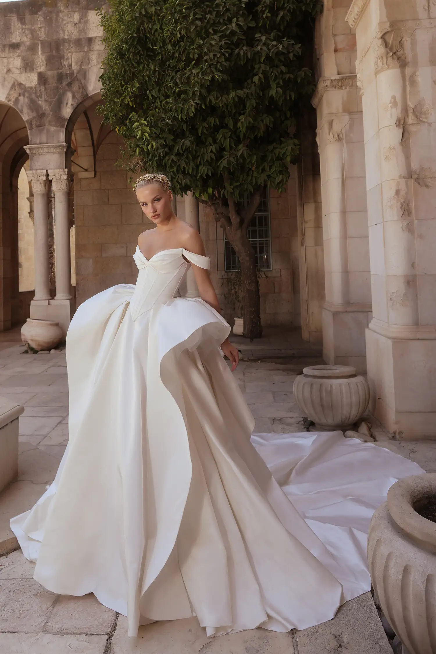 Matte satin ballgown with basque waist, draped sweetheart neckline and off-the-shoulder straps, and sculptural skirt ruffle detail.