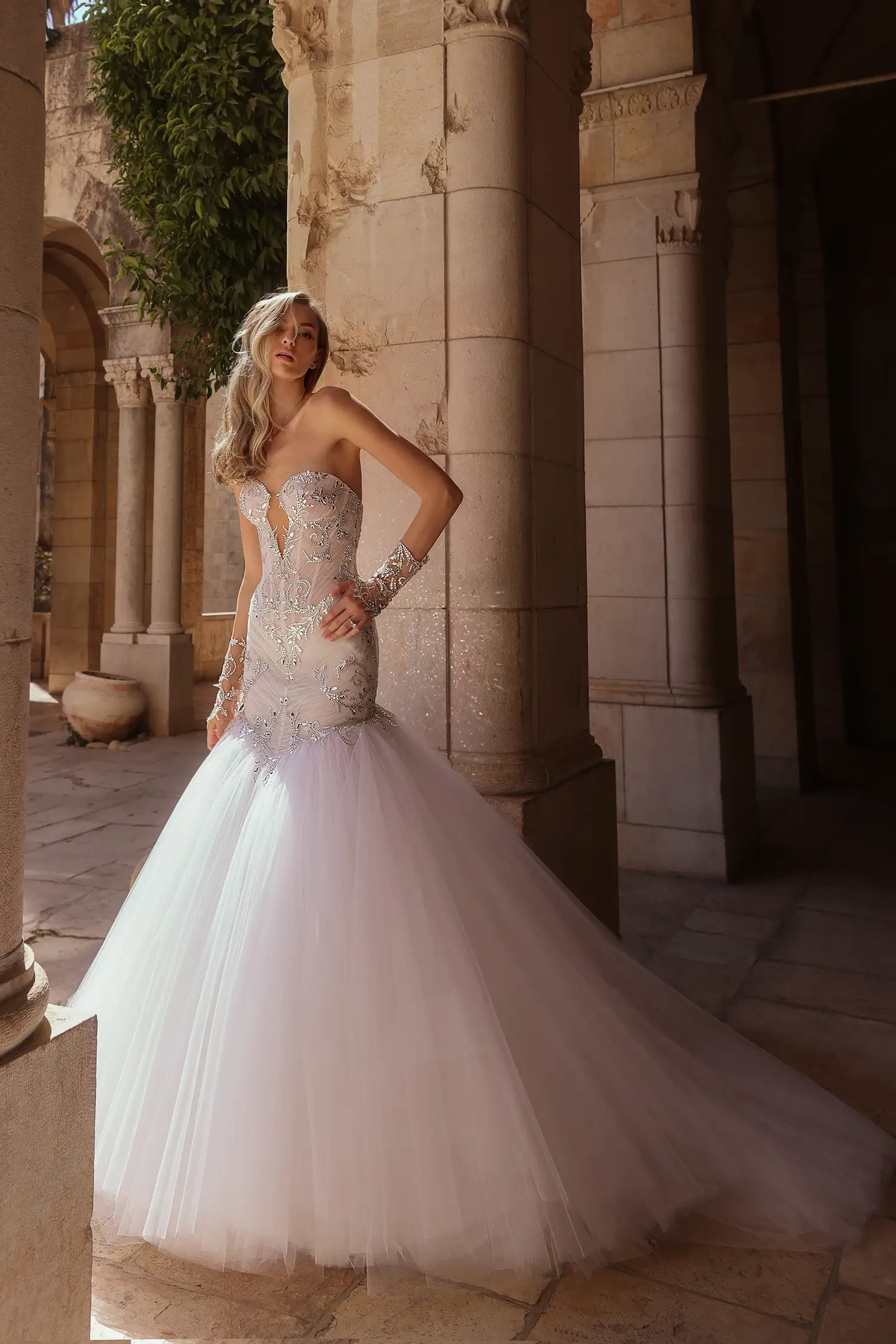 Strapless, sweetheart mermaid gown in tulle plissé fully embellished in mirror crystals. Shown with mirror crystal appliqué illusion gauntlet gloves and cathedral-length mirror crystal mantilla veil.