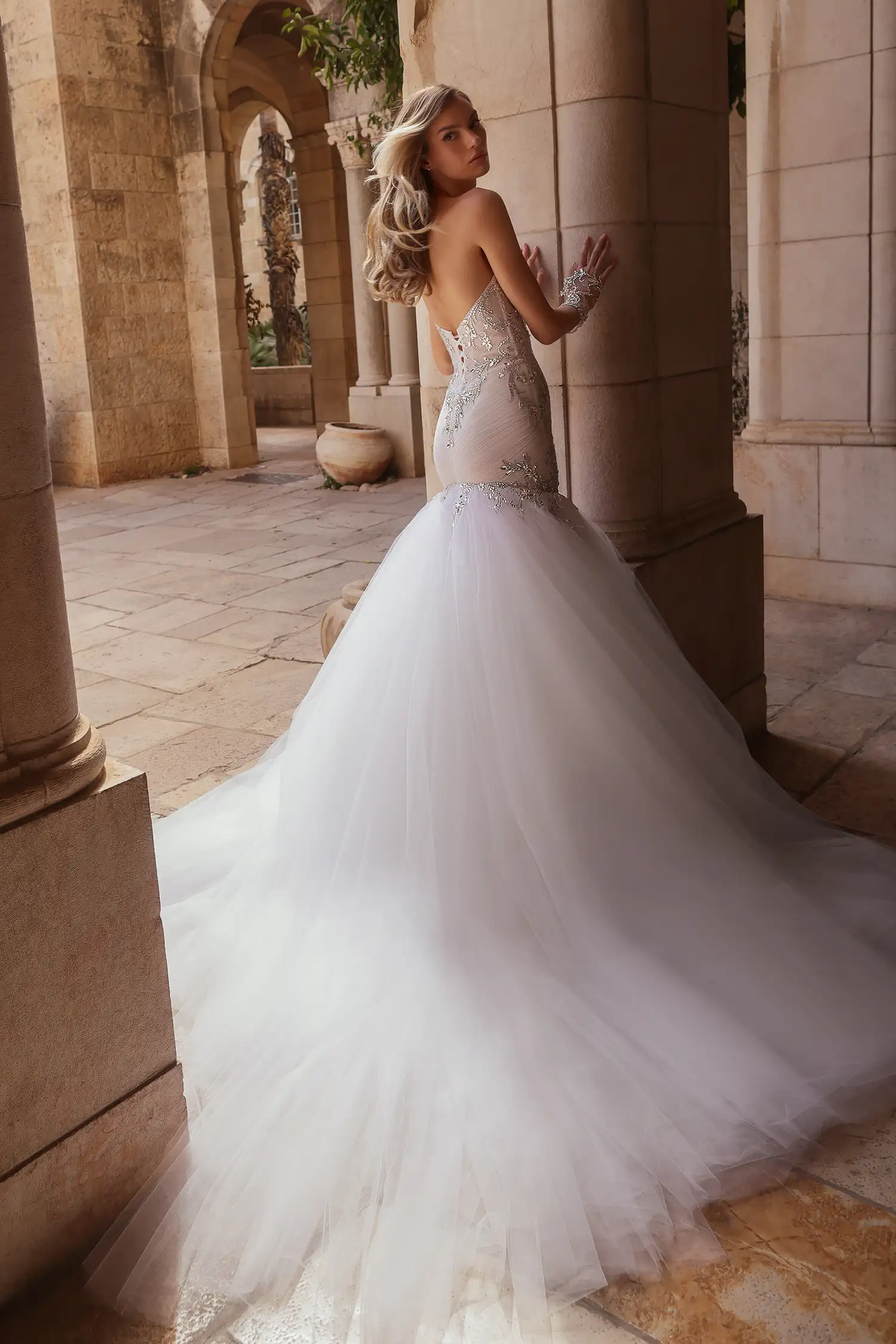 Strapless, sweetheart mermaid gown in tulle plissé fully embellished in mirror crystals. Shown with mirror crystal appliqué illusion gauntlet gloves and cathedral-length mirror crystal mantilla veil.