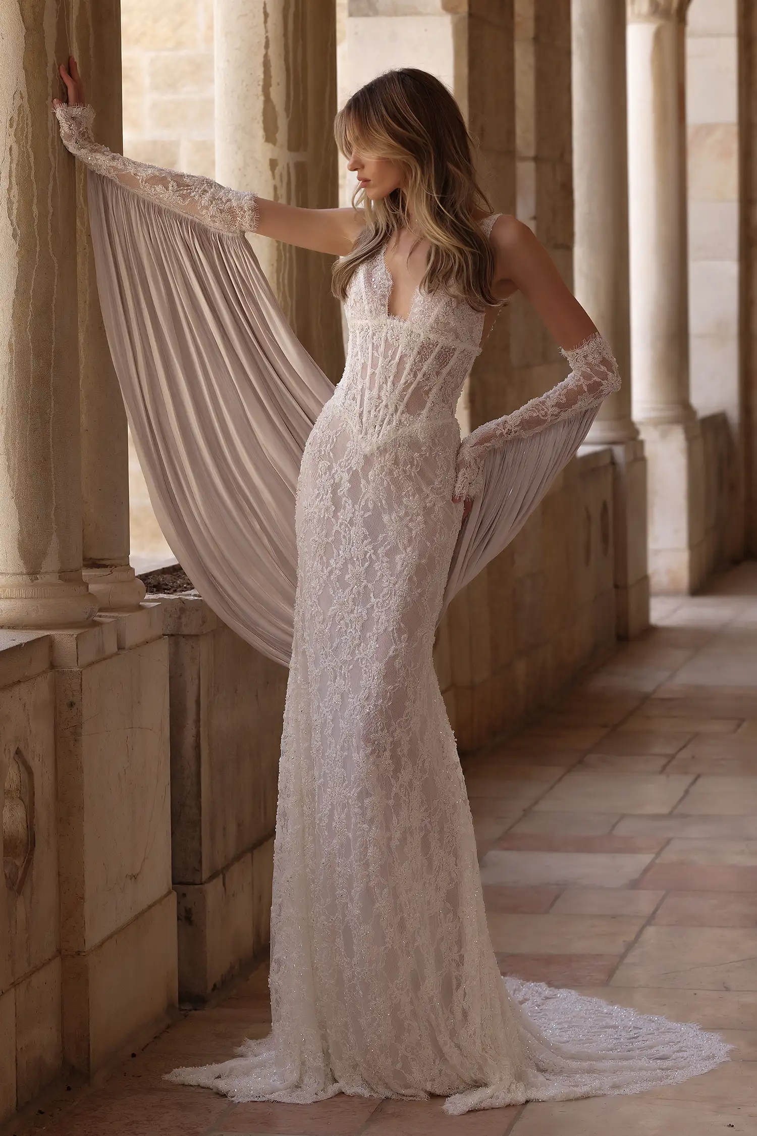 Beaded chantilly lace sheath gown with plunging neckline and underbust basque waist corset with exposed boning. Shown with beaded chantilly lace gauntlet gloves with draped liquid organza cape.