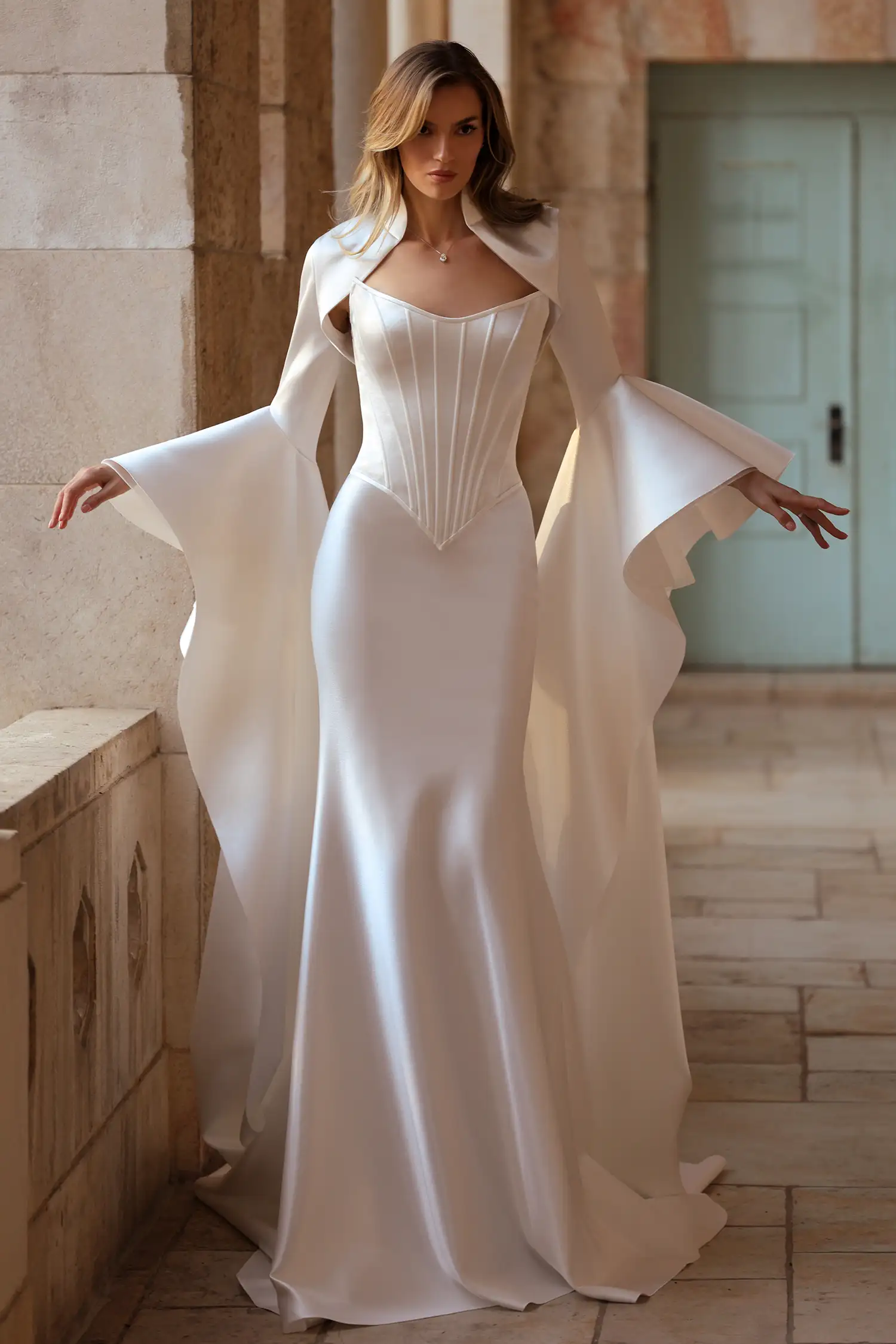 Strapless doubleface satin fit-and-flare gown with basque waist corset, shown with high collar doubleface satin bolero with dramatic floor-length sleeves. 