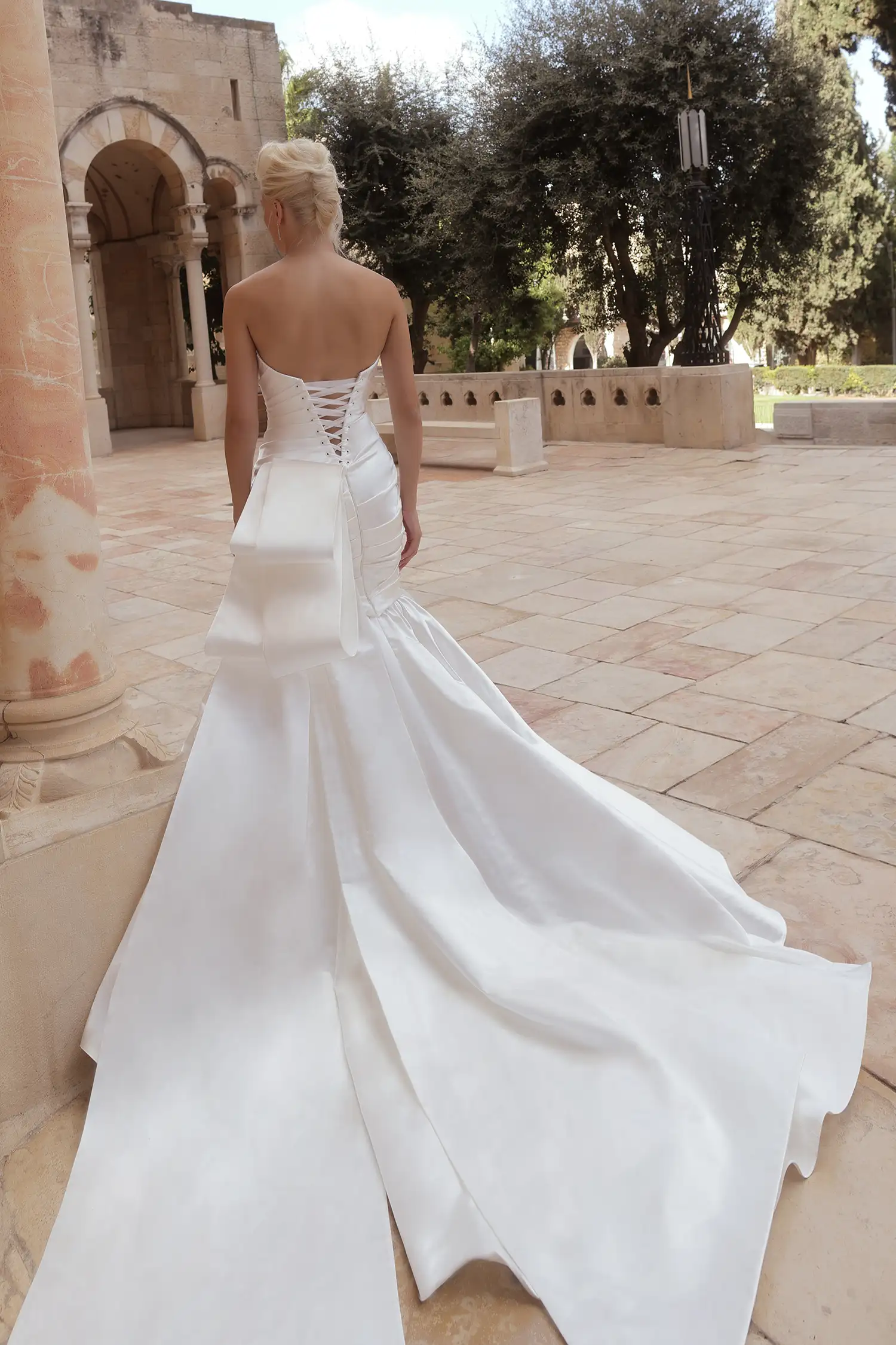 Draped strapless, straight-neckline mermaid gown in silk satin with signature Pnina bow.