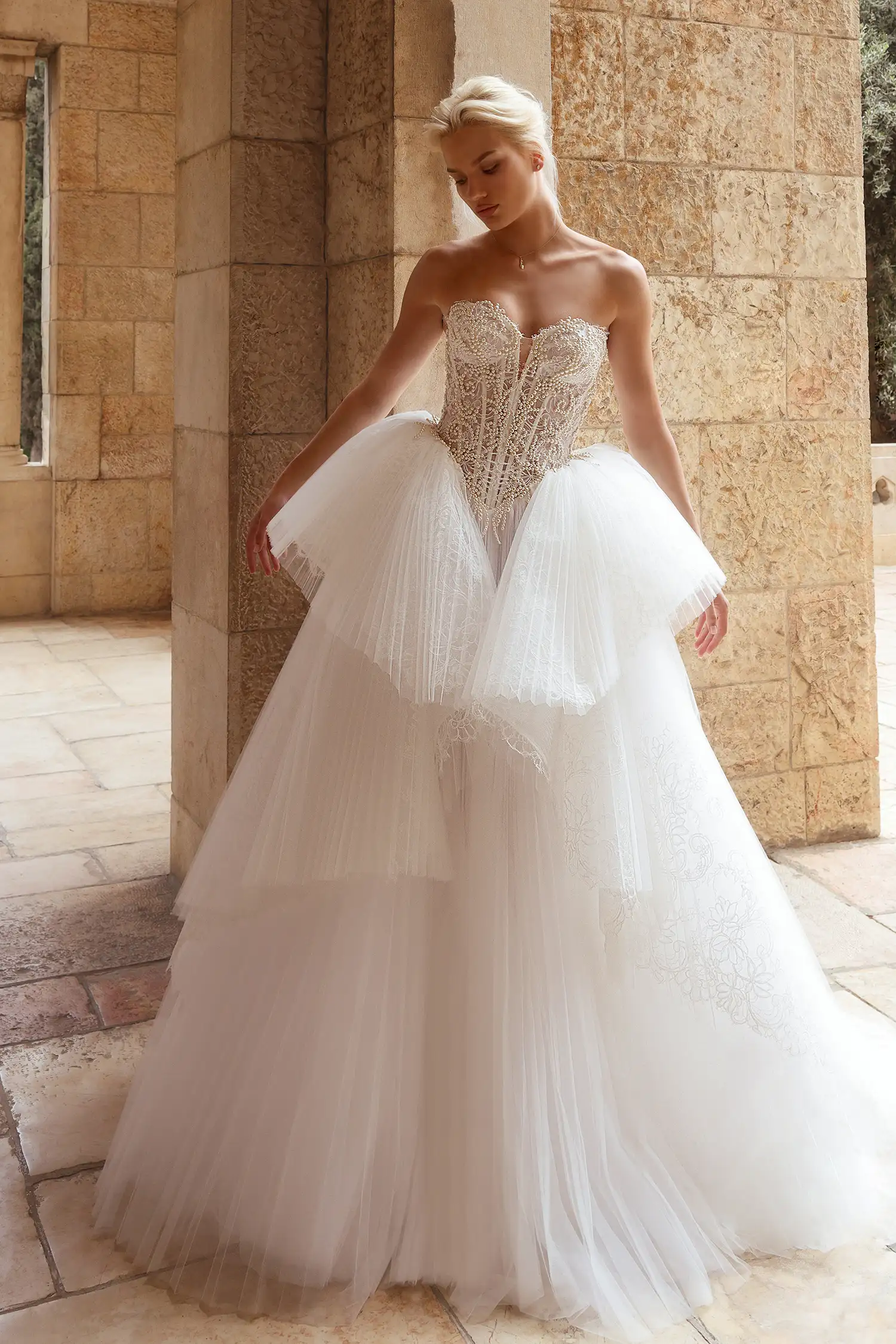 Strapless sweetheart ballgown in alençon lace and sunray pleated tulle, with structural lace and tulle ruffle skirt. Shown with cathedral-length veil with alençon lace border and lace gauntlet gloves with pleated tulle cuff detail.