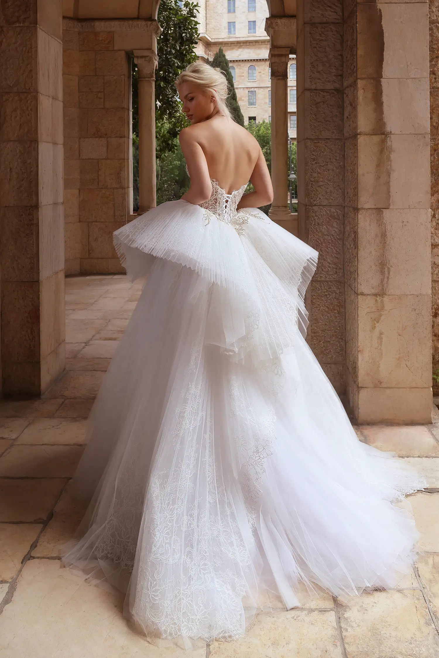 Strapless sweetheart ballgown in alençon lace and sunray pleated tulle, with structural lace and tulle ruffle skirt. Shown with cathedral-length veil with alençon lace border and lace gauntlet gloves with pleated tulle cuff detail.