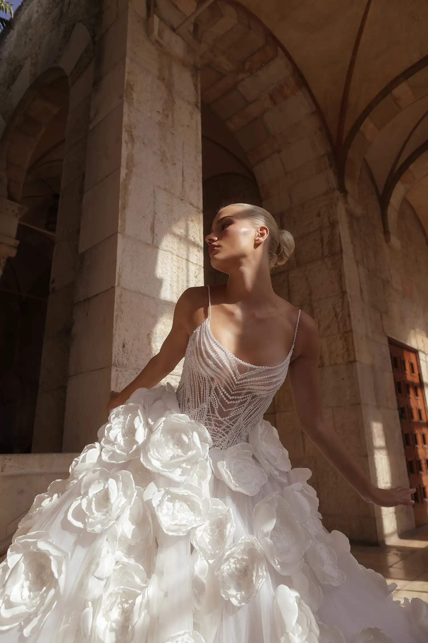 Ballgown with hand-beaded pearl bodice, satin dimensional flower skirt with pearl details, and pearl off-the-shoulder straps.